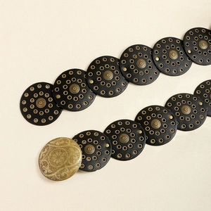 Dettaglio di cintura bohémien vintage con dischi in pelle e borchie in metallo bronzo