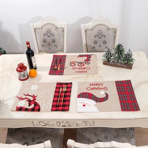 Detail of Christmas table mat with Santa and reindeer motifs on red black plaid linen