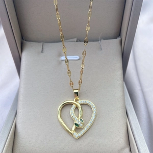 Detail of 18K gold heart necklace with snake motif and green zircon eyes