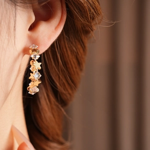 Close-up of sparkling star-shaped zircon C-hoop earrings worn by a model