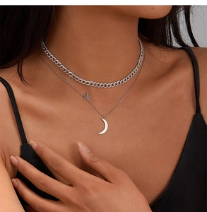 Detailed close-up of a silver-tone double-layered necklace featuring star and moon pendants