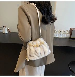 Detail of white striped faux fur bucket bag with resin bead chain on model shoulder