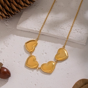 Dettaglio della collana in acciaio inossidabile dorato con cinque pendenti a cuore su pietra