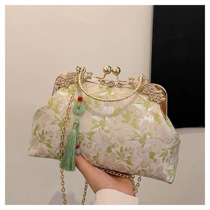 Close-up of beige jacquard handbag with green leaf embroidery and golden metal clasp