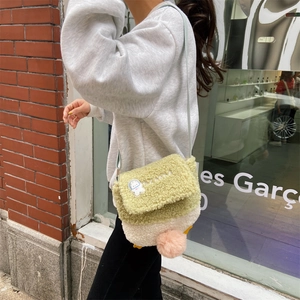 Detail of cute lamb wool duck crossbody bag with plush texture and embroidered astronaut patch