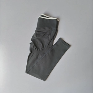 Macro shot of high-waist grey yoga leggings featuring contrast white trim and ribbed texture