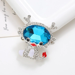 Macro shot of silver dragon charm with blue gemstone and crystal inlay on a white card