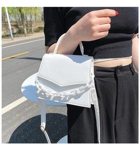 Detail of white square handbag with thick matte chain and gold-toned metallic hardware