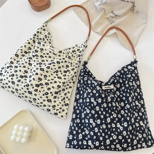 Détail de sacs cabas en toile florale avec anses en cuir aux motifs noir et blanc