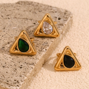 Macro detail of 18K gold plated triangle rings with teardrop gemstones on a stone base