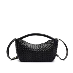 Close-up of black leather woven handbag with matching handle and adjustable strap detail