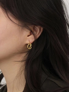 Elegant 925 sterling silver knotted hoop earrings in gold finish on a female model