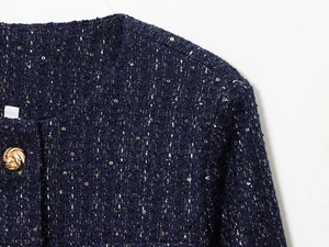 Detail der dunkelblauen Tweed-Jacke mit goldenen Knöpfen und Paillettenwebung