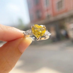 Outdoor close-up of heart-shaped yellow zircon ring with silver setting and side stones