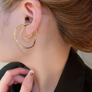 Detailed view of an irregular twisted gold ear cuff on a model's ear for styling
