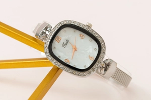 Close-up of Tadi silver mesh watch featuring a crystal-set oval shell dial and quartz movement
