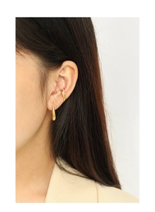 Close-up of a gold waterdrop earring and sparkling ear cuffs set on a model