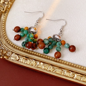 Detail view of bohemian wood and turquoise bead cluster earrings on a vintage background