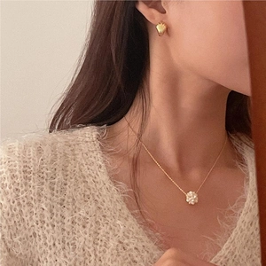 Detail of elegant gold shell earrings and pearl flower necklace worn with knitwear