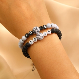 Close-up of 2026 World Cup beaded bracelets with soccer charms on a silk background