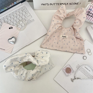 Dettaglio di mini borse in cotone a fiori blu, disponibili nei colori rosa e beige