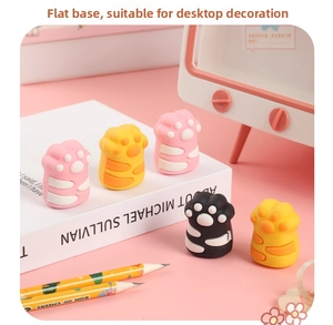 Close-up of cute cat paw shaped erasers in pink, yellow and black on a desk