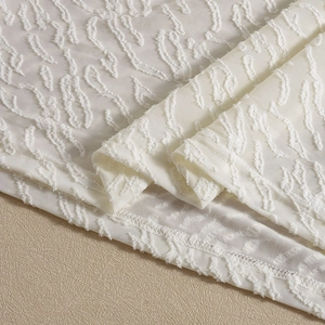 Makrodetail eines weißen Kleiderstoffs mit komplexer 3D-Struktur und Jacquard-Muster