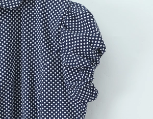 Dettaglio ravvicinato della manica a sbuffo blu navy con motivo a pois bianchi su tessuto