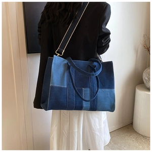 Detail view of denim patchwork tote bag with gold hardware and white stitching details