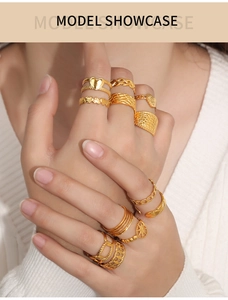 Detail view of layered gold rings with textured heart and star patterns on a model's hand