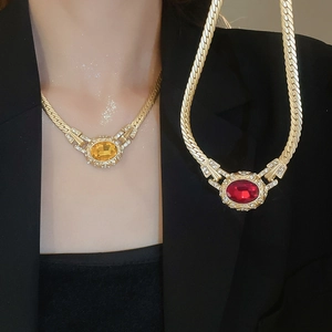 Detail of vintage gold oval pendant necklaces with red and amber stones and crystals