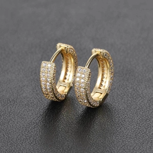 Macro shot of gold hoop earrings for men with pavé diamonds on a black background