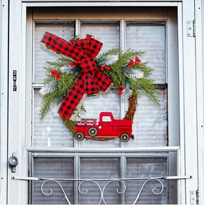 Details des Weihnachtskranzes mit rotem LKW und Karoschleife an weißer Haustür