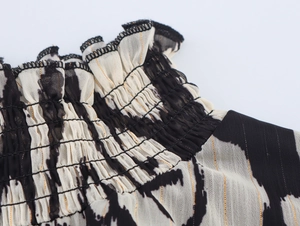 Detailed macro view of smocking on ethnic print chiffon fabric with gold metallic thread