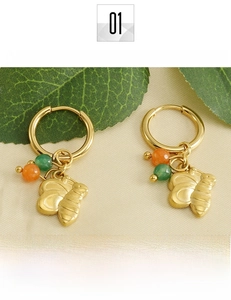 Détail de boucles d'oreilles créoles en acier titane doré 18k avec breloques abeilles