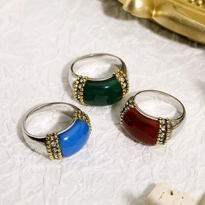 Three titanium steel rings with colorful cat eye stones on a white textured background
