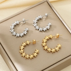 Detailed view of gold and silver star-shaped C-hoop earrings on a leather jewelry tray