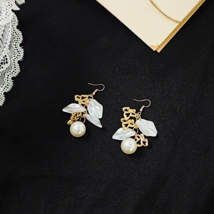Macro detail of French vintage gold earrings with white petals and elegant large pearls