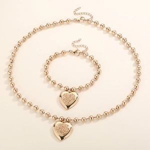 Detail of gold beaded heart pendant necklace and bracelet set with sparkling crystals