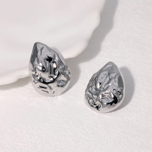Gros plan de boucles d'oreilles en acier argenté avec texture lave et fini métal fondu