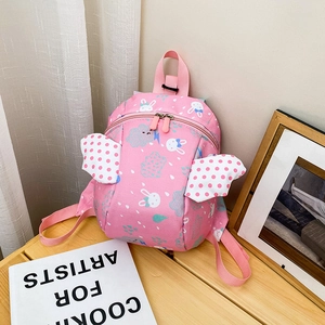 Pink toddler backpack with angel wings and rabbit pattern on light wood table