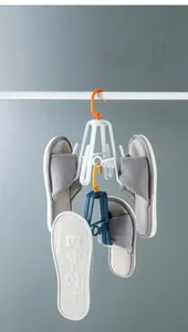 Rotating shoe drying rack with hooks holding grey slippers against a grey wall