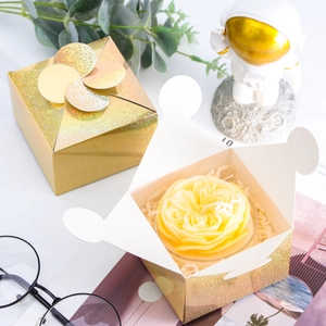 Detail of golden laser paper gift box with rose candle and decorative holiday packaging