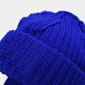 Dettaglio del berretto in maglia blu reale con trama spessa e finiture delle cuciture