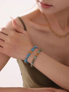 Detail of layered turquoise and green stone bead bracelets with 18k gold plated accents
