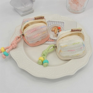 Detail view of two cute tweed fabric earphone storage pouches in soft pink and white colors