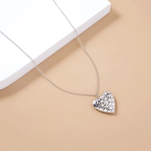 Dettaglio della collana con medaglione a cuore d'argento traforato con motivi geometrici