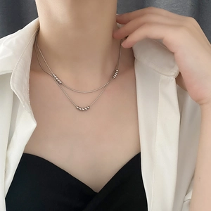 Minimalist double-layered silver beaded necklace with snake chain worn on model neck