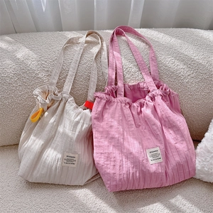 Detail of striped drawstring tote bags showing pleated texture and colorful ribbons