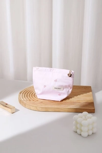 Detailed shot of pink heart embroidered makeup bag with a gold flower zipper pull